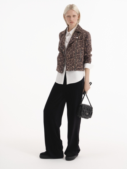 Model wearing leopard blazer, white blouse and black trousers, holding a braided handbag – an elegant look by STEFFEN SCHRAUT.
